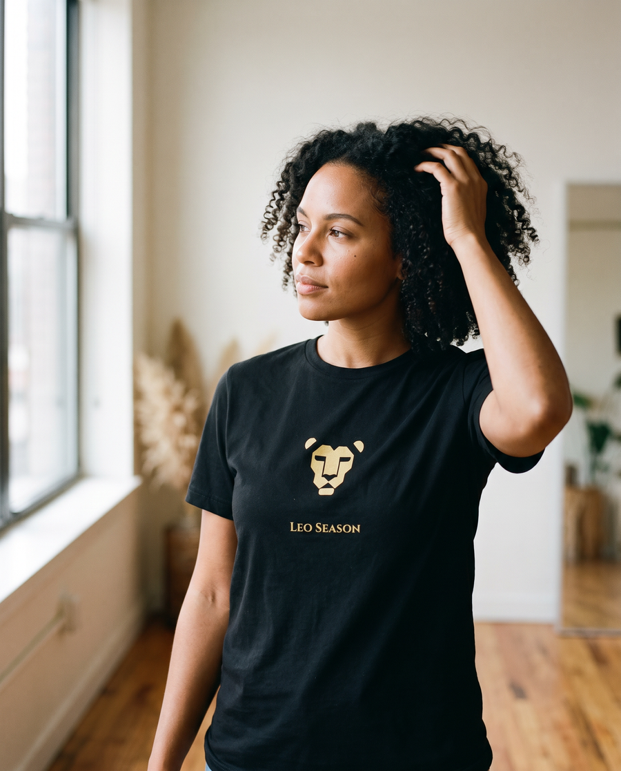 Woman wearing the Lioness Fire Tee in Black by a sunlit window